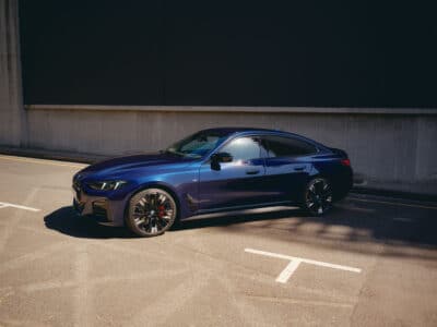 Ein BMW M4 parkt vor einem modernen Gebäude, das die sportliche Eleganz des Fahrzeugs unterstreicht.