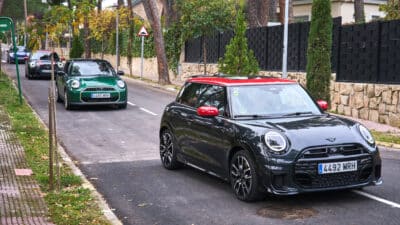 4 bunte MINI Cooper fahren hintereinander in einer Wohngegend