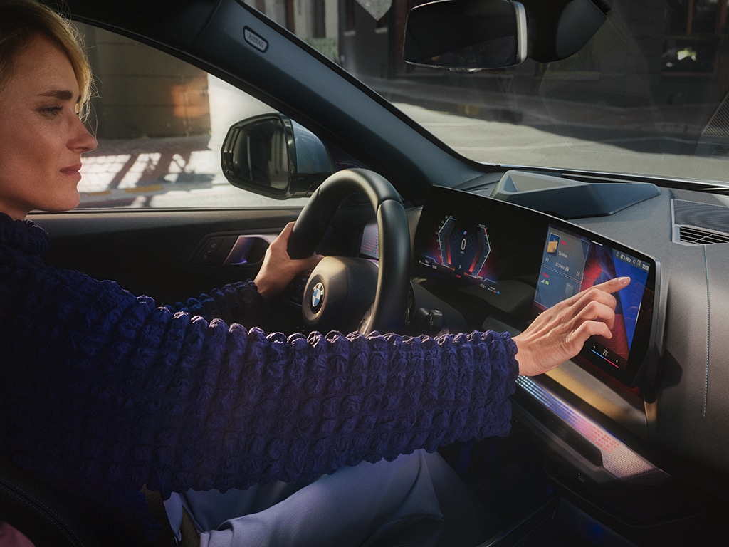 Eine Frau bedient das Navi bei einem 1er BMW