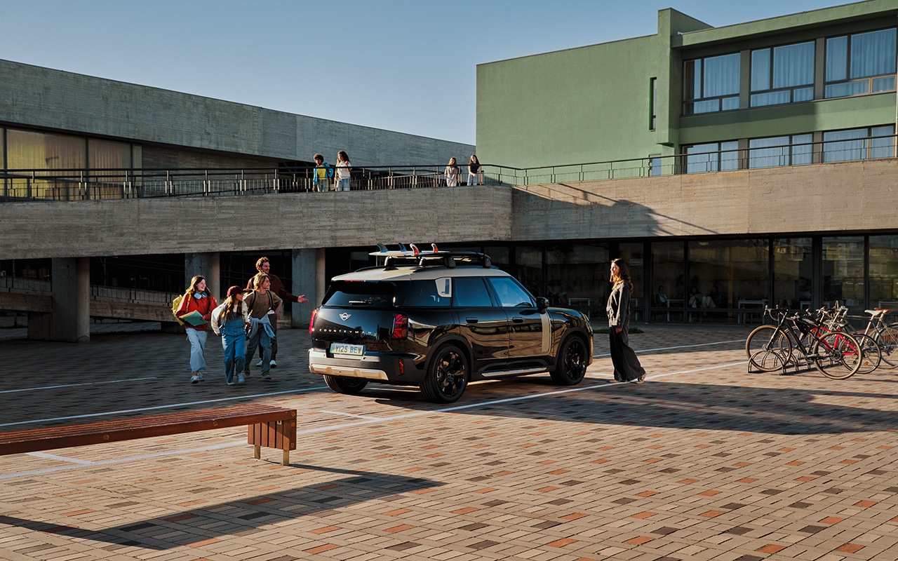 MINI Countryman im urbanen Lifestyle-Setting auf einem Campus, Menschen bewegen sich dynamisch rund um das Fahrzeug.